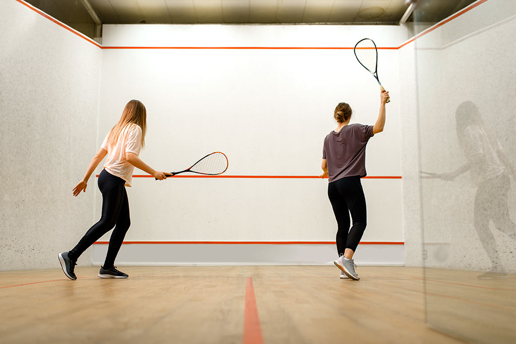 Two female players with rackets, squash game on court. Girls on training, active sport hobby, fitness workout